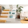 Kép 2/2 - Kék CURVER 'SOFTEX' 4 literes tárolókosár, mintás felülettel, a lépcsőn elhelyezve. A modern, világos nappaliban egy zöld növény és bézs kanapé mellett található, barátságos, esztétikus környezetben.