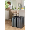 Kép 3/3 - Két CURVER 'VERTO RECYCLE' 54L szemetes, modern gyöngyház hatással, a konyhában, mellette egy nő a mosogatónál dolgozik. A kukák széles, érintőfelülettel nyitható fedéllel rendelkeznek, és újrahasznosítási matricák rögzíthetők.