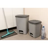 Kép 6/7 - Modern, szürke CURVER 'ESSENTIALS' szemetesek, egy 40L-es és egy kisebb változat, pedálos nyitási mechanizmussal, konyhai környezetben elhelyezve, takarítóeszközzel és egy vízpalackkal a háttérben.