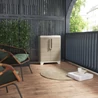 Kép 4/4 - Modern, világos bézs/sárga színű KETER Split Premium Wood szelektív hulladékgyűjtő, zárható rekeszekkel, kültérben elhelyezve. A fa hatású tároló mögött zöld növények és kényelmes kerti széksor található.