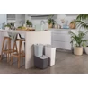 Kép 7/11 - Három CURVER 'READY TO COLLECT' szelektív hulladékgyűjtő kosár (20L, 10L, 5L) látható egy modern konyhában, különböző színekben (szürke, fehér, világoskék), egymásra helyezve, mellettük étkezési alapanyagokkal teli vágódeszka.