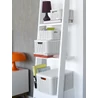 Kép 3/4 - Fehér rattan kosarak a létrára helyezve, különböző méretekben, egy elegáns nappali háttérben, színes iratokkal és lámpával. A kosarak fedi a tárolást, míg a létra stílusos elrendezést biztosít.