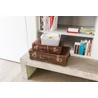 Kép 4/6 - Krémszínű, rattan hatású CURVER 'MY STYLE' S méretű kosár, kézreálló fogantyúkkal, egy vintage bőröndökkel díszített, modern nappaliban helyezkedik el, tárolási lehetőséget kínálva.