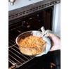 Kép 3/7 - Kézben tartott boroszilikát üvegből készült CURVER 'SMART COOK' 1,2 literes ételtartó, frissen sütött étellel, amelyet éppen a sütőből emelnek ki. Az ételtartó sütőbe helyezhető, BPA-mentes műanyag tetővel rendelkezik.
